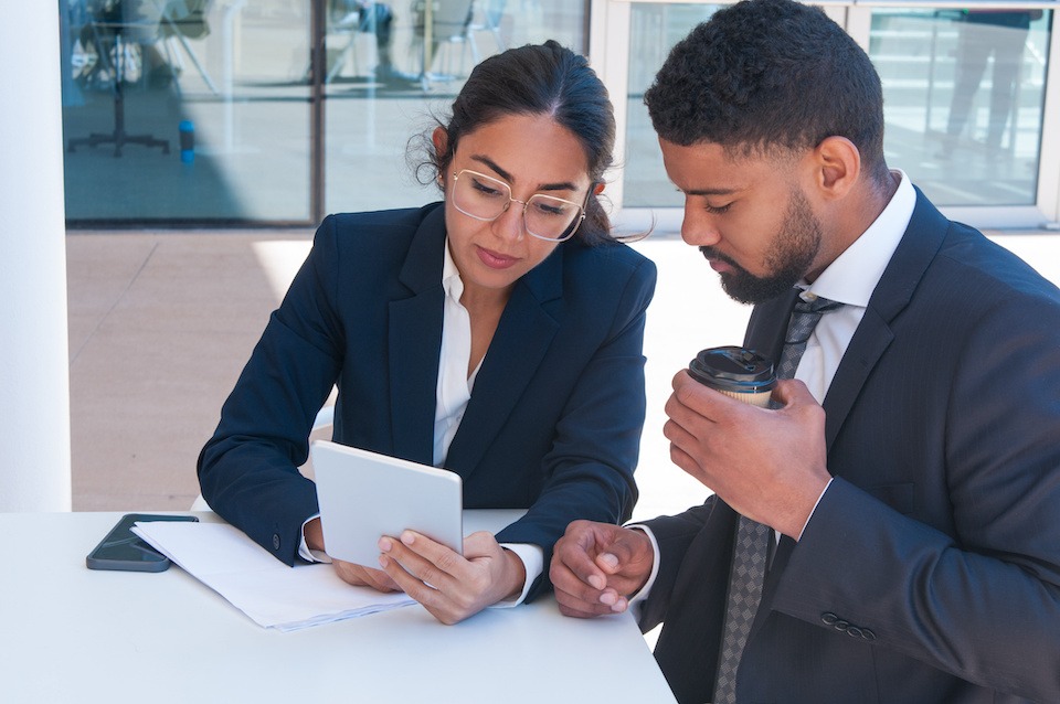 Business people using tablet computer at cafe table